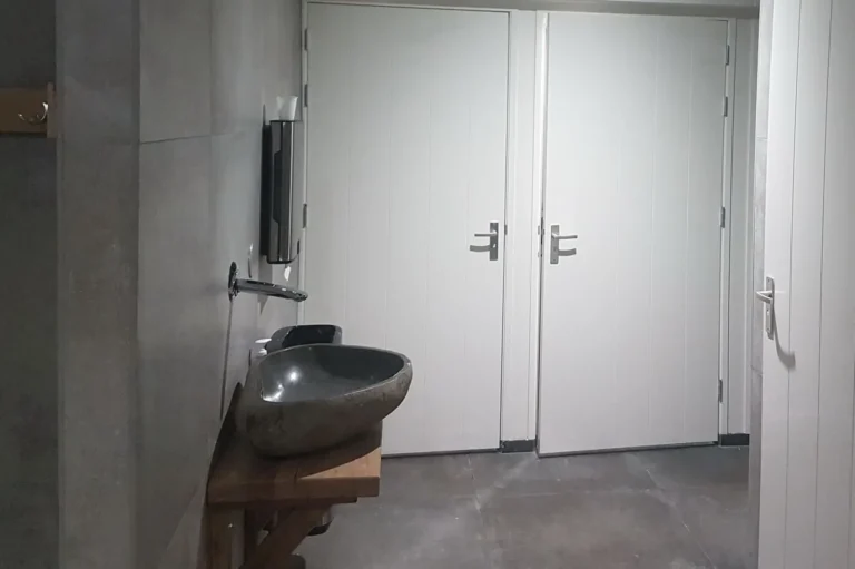 Betegelde ruimte met wastafel en dubbele deuren